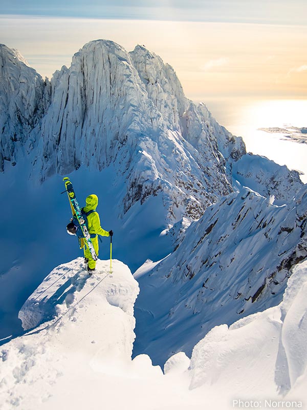 Man wearing Norrona skiwear looking over snowy mountain scene